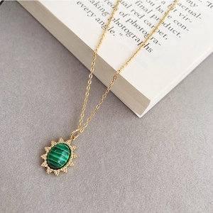 Gros plan du collier étoile dorée avec pierre de malachite verte sur un livre vintage