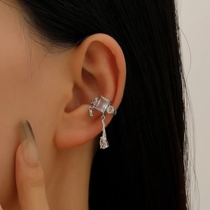Macro view of silver ear cuff with rectangular and teardrop zircon pendants on ear