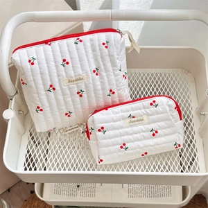 Close-up of quilted cherry print toiletry bags in two sizes with red zipper detail