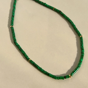 Close-up of green malachite textured beads and gold disc spacers on beaded necklace