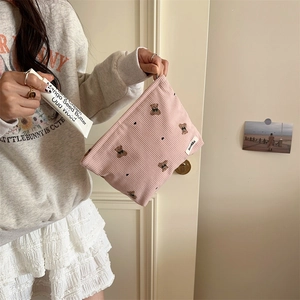 Detail of pink corduroy makeup bag with cute bear embroidery and smooth metal zipper