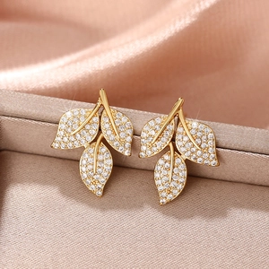 Elegant gold leaf earrings with sparkling cubic zirconia on champagne silk background
