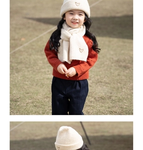Detail view of cream white knitted hat and scarf set with golden heart embroidery