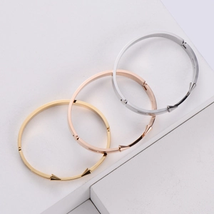Close-up of polished double spearhead bangles in gold, rose gold, and silver finishes