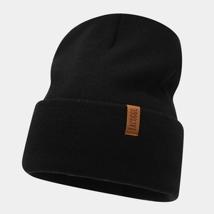 Close-up of black ribbed knit beanie featuring a brown leather patch with logo detail