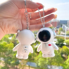 Detailed front and back views of two white astronaut keychains with silver accents