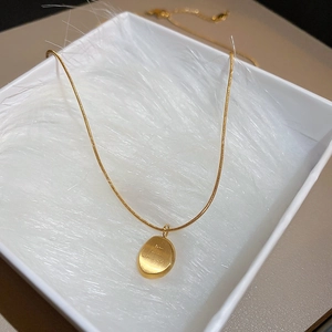 Détail d'un collier doré avec pendentif ovale présenté dans un écrin à bijoux en peluche