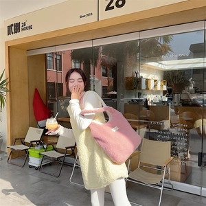 Detailed texture of pink plush tote bag and yellow fleece vest in outdoor sunlight