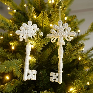 White glittery key-shaped Christmas ornaments hanging on a tree with warm fairy lights