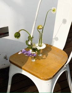 Artistic detail of a minimalist white acrylic vase with two glass test tubes and flowers