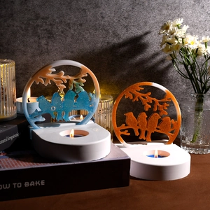 Close-up of bird and floral resin candle holder set with gradient blue and orange finish
