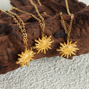 Three 18K gold plated sun pendant necklaces displayed on a rustic wooden sculpture base