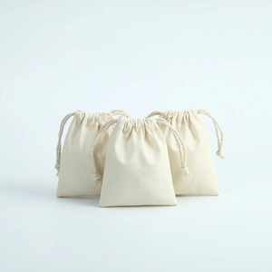 Macro shot of three natural cotton drawstring pouches showing high quality fabric texture