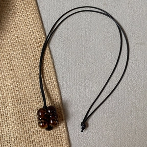 Detail of a brown amber-style beaded cluster pendant on an adjustable black cord necklace