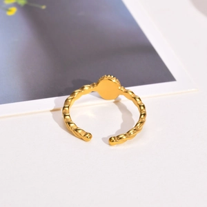 Detailed macro view of gold twisted ring band featuring a round black center element
