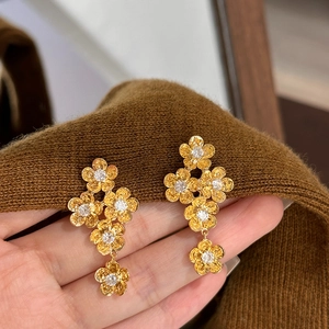Vintage gold floral drop earrings with white zircon crystals shown in hand