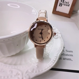 Elegant rose gold quartz watch with beige leather strap on a decorative plate