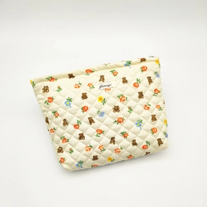 Quilted makeup bag with brown bear and colorful floral patterns on cream fabric