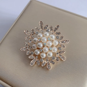Elegant gold snowflake brooch with pearls and sparkling rhinestones on jewelry box