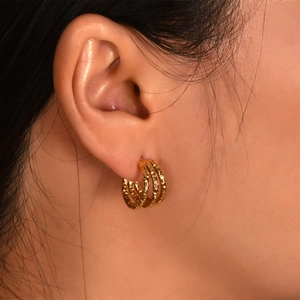 Detailed close-up view of triple line C-shaped gold plated twisted hoop earrings.