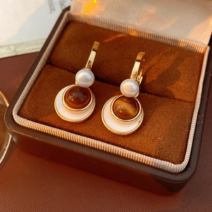 Detailed macro view of vintage gold earrings with pearls and amber stones in a jewelry box