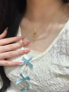 Detail of a gold rocking horse pendant necklace with zircon inlay worn by a model