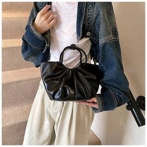 Close-up of black pleated cloud bag in shiny leather with double round handles