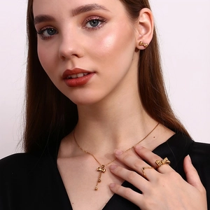 Close-up of golden bow jewelry set including necklace, ring and studs worn by a model