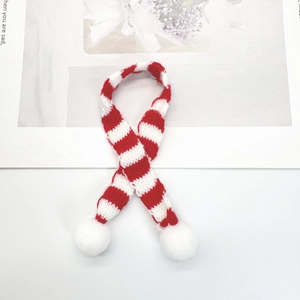 Close-up of a red and white striped mini knitted scarf with fluffy white pom-poms