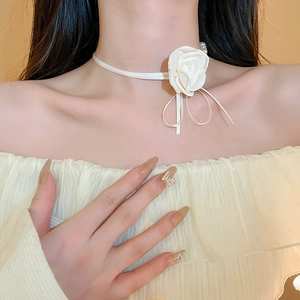 Détail d'un collier ras du cou fleur en tissu avec nœud ruban blanc sur un mannequin