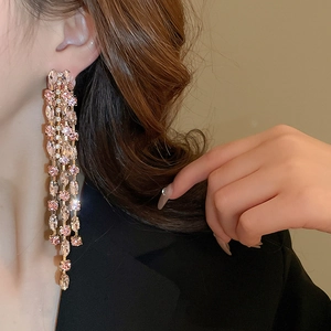 Close-up of long geometric tassel earrings with pink rhinestones on a female model