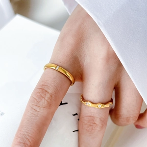 Detail of minimalist gold-plated rings with small zirconia stones on a white background