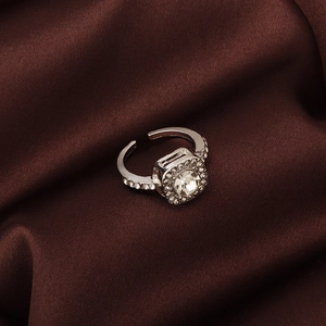 Detailed close-up of a silver ring with a square zircon gemstone on brown silk fabric