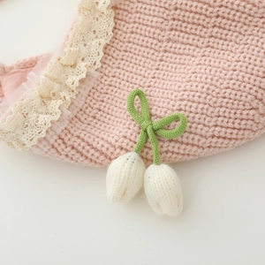 Detail of baby knit hat featuring vintage beige lace trim and 3D tulip floral decor