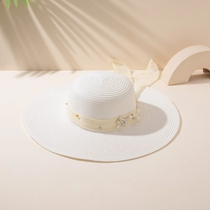 Close-up of white straw sun hat with yellow satin bow, flowers, and pearl accents