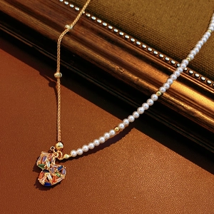 Detail of 18k gold plated necklace with rainbow zircon heart and pearl chain on leather