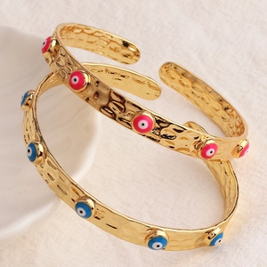 Dettaglio macro del bracciale martellato placcato oro con motivi occhio in smalto colorato