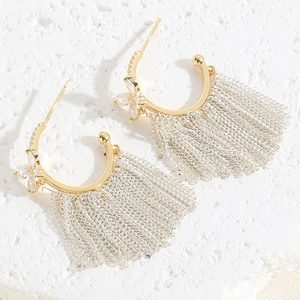 Close-up of zircon earrings featuring chain tassels and gold C-shaped metal hoops