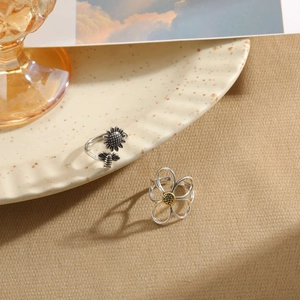Detail of vintage S925 silver bee and sunflower ring with antique finish on ceramic plate