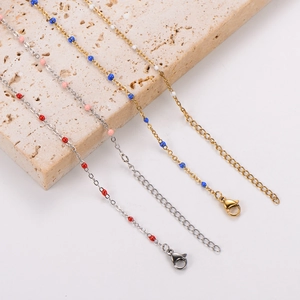 Detail of 18k gold and silver O-chain anklets with colorful enamel beads on stone