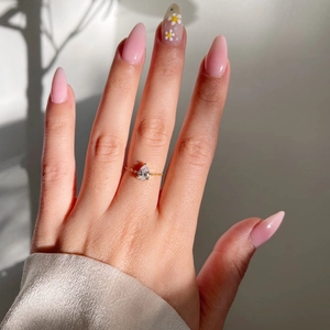 Détail d'une bague goutte d'émeraude plaquée or avec chaîne réglable sur un doigt