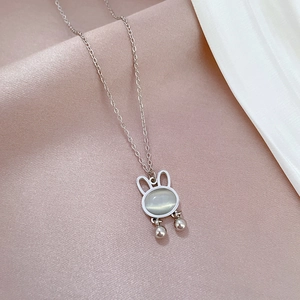 Macro detail of opal rabbit pendant necklace in titanium steel on silk background