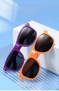 Close-up of stylish purple and orange sunglasses with silver metal rivets on a white stand
