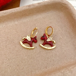 Détail macro de boucles d'oreilles cheval à bascule en émail rouge et zircons dorés