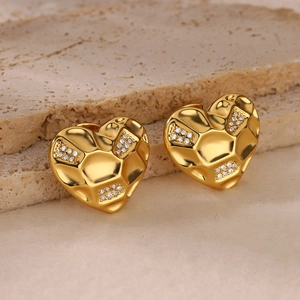 Macro view of 18K gold heart earrings with hammered texture and zircon inlays