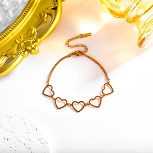 Detailed view of hollow heart charms on a gold stainless steel link bracelet on white