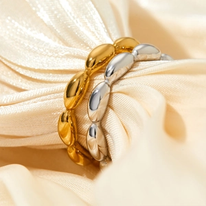 Polished gold and silver stainless steel rings with texture on beige satin fabric