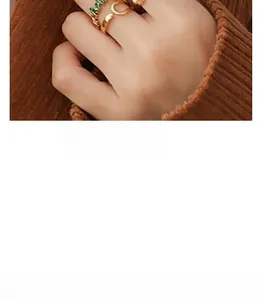 Close-up of three-piece vintage gold ring set featuring green gemstones on a model hand