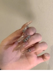 Vue détaillée de faux ongles rose nude avec des nœuds métalliques argentés et pois noirs