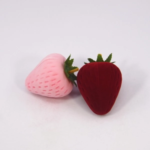 Macro detail of strawberry-shaped velvet jewelry boxes in pink and red tones